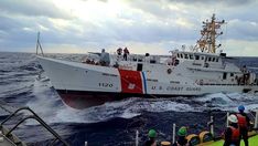 the coast guard boat is in the middle of the ocean as people watch from the deck