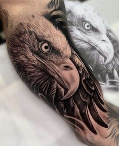 an arm with two eagle tattoos on it and one is black and grey, while the other is white