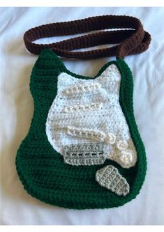 a crocheted purse with a white and green cat on it's side