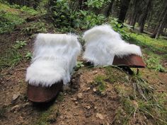 furry white slippers sitting on top of a forest floor