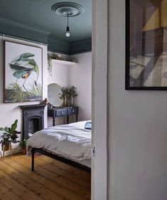 a bedroom with a bed, dresser and painting on the wall in it's corner