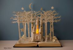 an open book with paper cut out of it and trees on the pages that are lit up