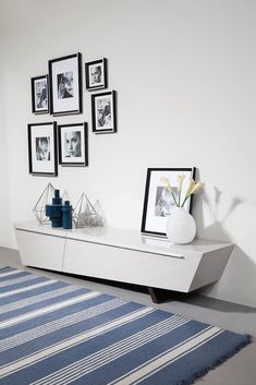 a living room with pictures on the wall and a blue rug in front of it