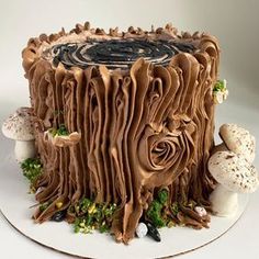 there is a cake that looks like it has been carved into a tree stump with leaves and mushrooms around it