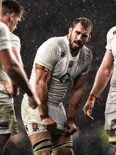 three rugby players are standing in the rain