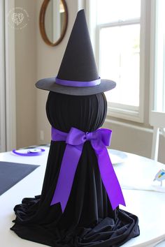 a black and purple hat on top of a table with a purple ribbon around it