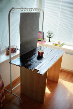 a wooden table with a cup on it in the middle of a room next to a window