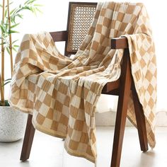 a chair with a checkered blanket on it next to a potted bamboo plant