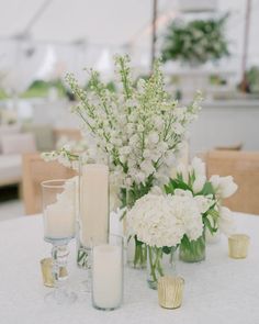 white flowers and candles on a table in a tented area at a wedding reception