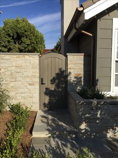 an entrance to a house with a stone wall and planter in the foreground