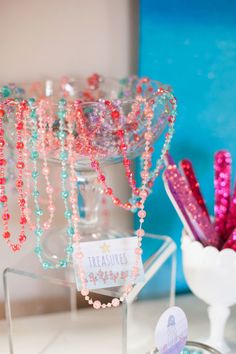 there are many beads on display in the glass vases, and one has a name tag that says treasures