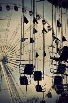 an amusement park ferris wheel with lots of seats hanging from it's sides and the sky in the background