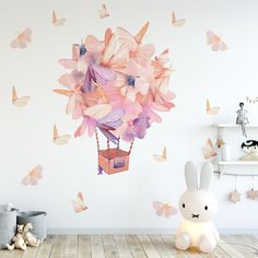 a white rabbit sitting in front of a wall with butterflies on it and a hot air balloon