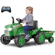 a young boy riding on the back of a green tractor with remote controls in front of him