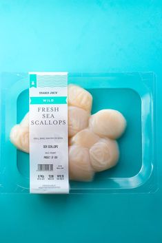 fresh sea scallops in a plastic container on a blue background with a label