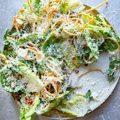 a white plate topped with lettuce covered in parmesan cheese and other toppings