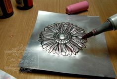 a metal plate with a flower on it and some paint bottles next to the tray