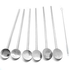 six spoons are lined up next to each other on a white surface with silverware in the middle