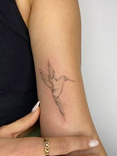 a woman's arm with a small bird tattoo on it