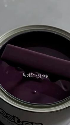 an open can of violet - black paint on a white surface