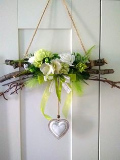 a white flower arrangement hanging from a door with a heart shaped ornament on it