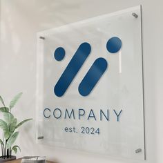 a glass sign hanging from the side of a wall next to a potted plant