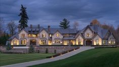 a large house lit up at night with lights on the windows and steps leading to it