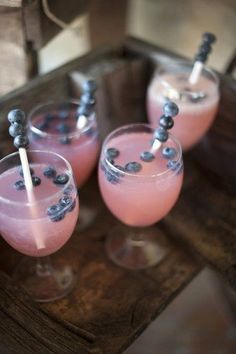 three glasses filled with blueberries on top of a wooden table next to each other