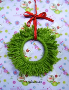 a green wreath with a red bow hanging on a tablecloth covered wall ornament