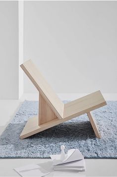 a wooden chair sitting on top of a blue rug next to sheets of white paper