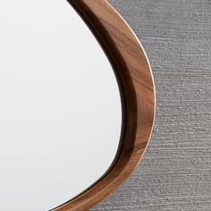 a round mirror on the wall with a wooden frame and wood trim around it's edge