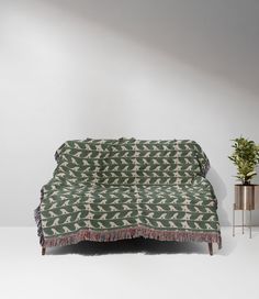 a green and white blanket sitting on top of a table next to a potted plant