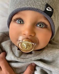 a baby with a pacifier in his mouth and wearing a beanie on it's head