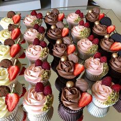 cupcakes with chocolate frosting and strawberries are arranged on a glass table