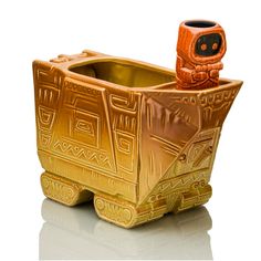 a gold colored ceramic container with an owl on it's head sitting in front of a white background