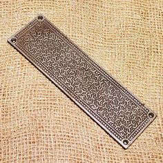 a decorative metal plate sitting on top of a piece of burlied fabric with holes in the middle