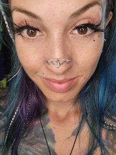 a close up of a person with blue hair and piercings on her nose,