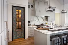 a large kitchen with white cabinets and marble counter tops, along with bar stools