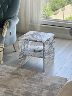 a blue chair sitting next to a white table on top of a hard wood floor