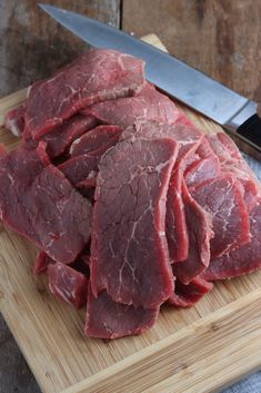 some raw meat on a cutting board with a knife