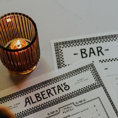 two menus sitting on top of a table next to a candle