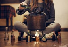 a woman is sitting on the floor with bottles around her and holding a bottle opener