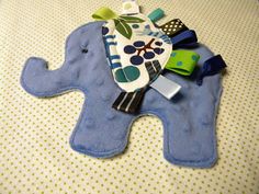 an elephant shaped toy on top of a bed with blue and green decorations around it