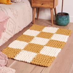 a yellow and white rug sitting on top of a wooden floor next to a bed