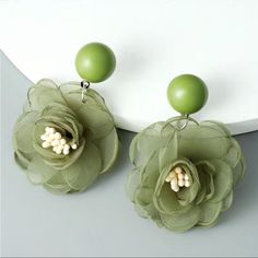 two green flower earrings with pearls hanging from the front and back of each earring