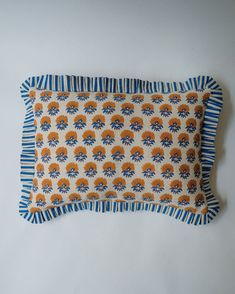 an orange and blue decorative pillow on a white background