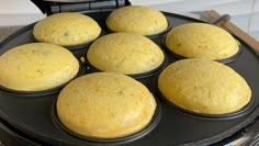 six muffins in a black pan on top of a stove burner, ready to go into the oven