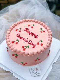 a pink birthday cake with cherries on it