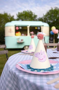 a birthday party with peppa the pig hat on a blue and white checkered table cloth