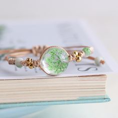 a close up of a book with a bracelet on it and a dandelion